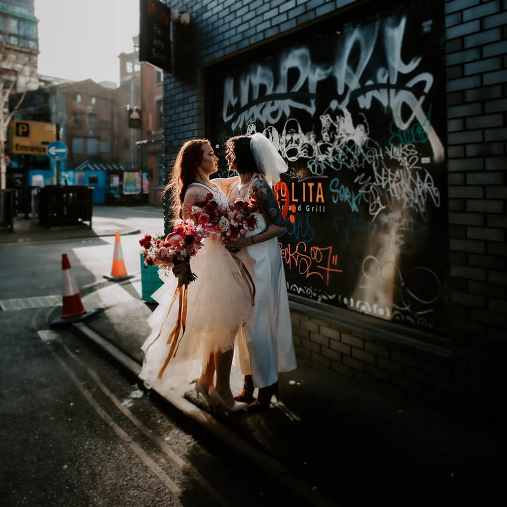 LGBTQI urban wedding photograph with two brides in a layered tulle weddng dress and satin slip 