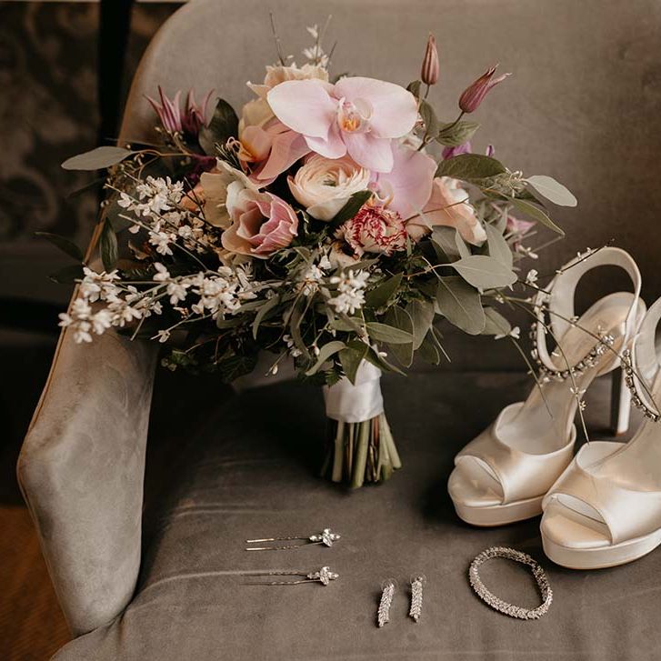Pink and white mixed floral bouquet next to cream dune scrappy wedding heels and silver jewellery 