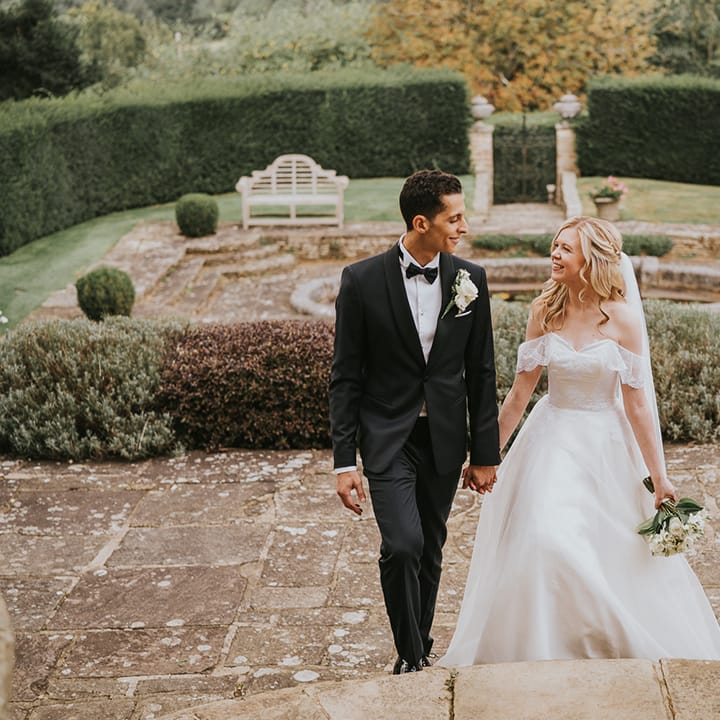 Bride and groom walk up stairs holding hands for their traditional wedding 