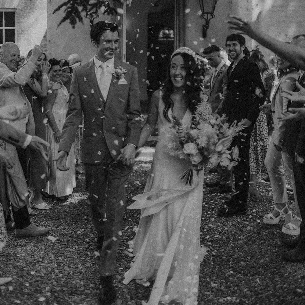 Bride and groom smile happily as they exit their wedding ceremony to confetti 