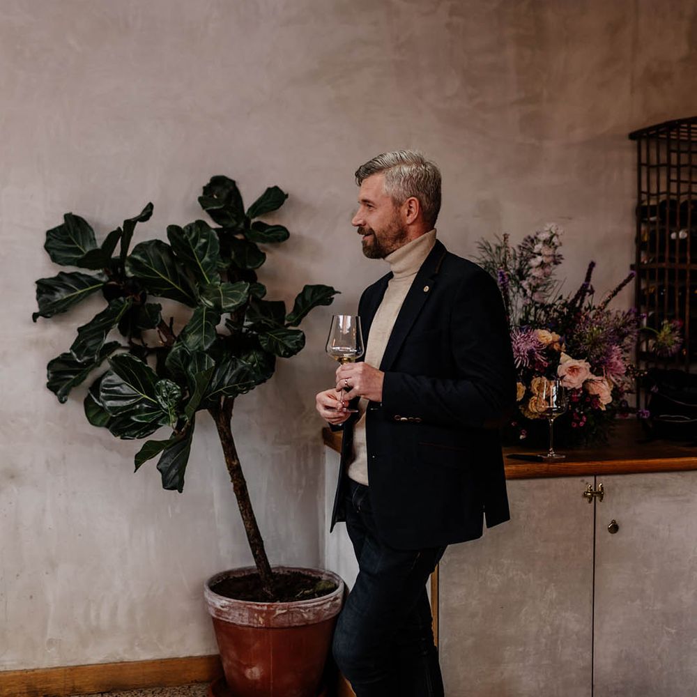 Wedding guest in a beige turtle neck and suit jacket giving a speech 