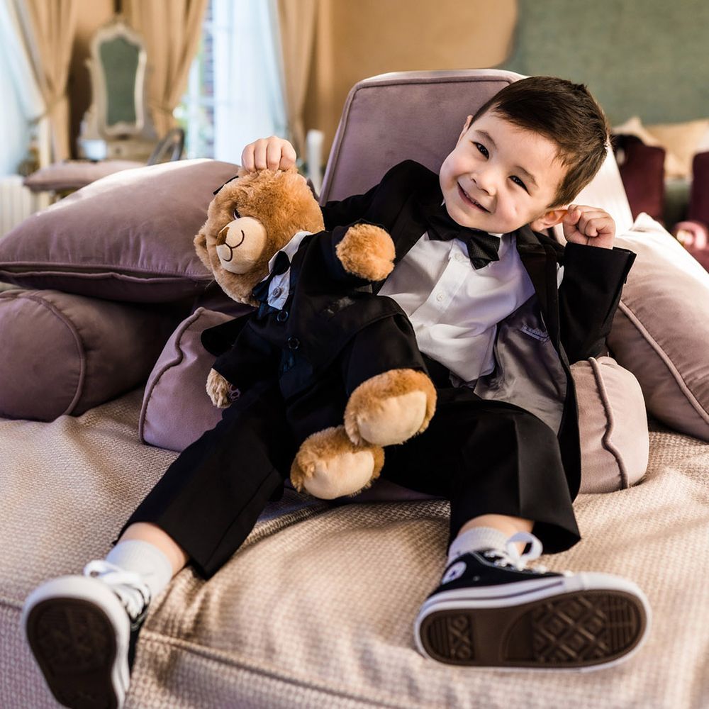 Young page boy in black tie with a teddy also wearing black tie 