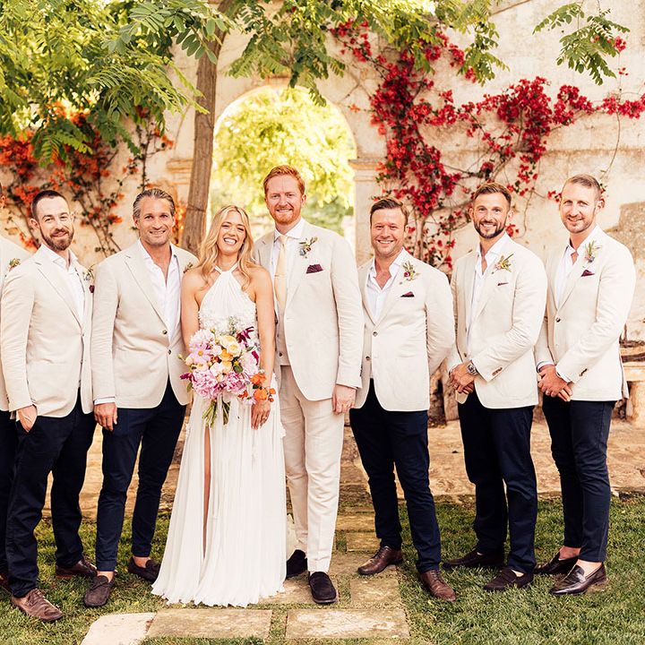 Bride and groom with the groomsmen in matching cream suits for the rustic destination wedding 