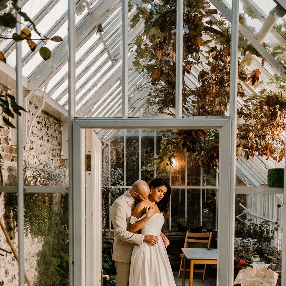Bride and groom share an intimate moment in the glasshouse at the Chapel House Estate 