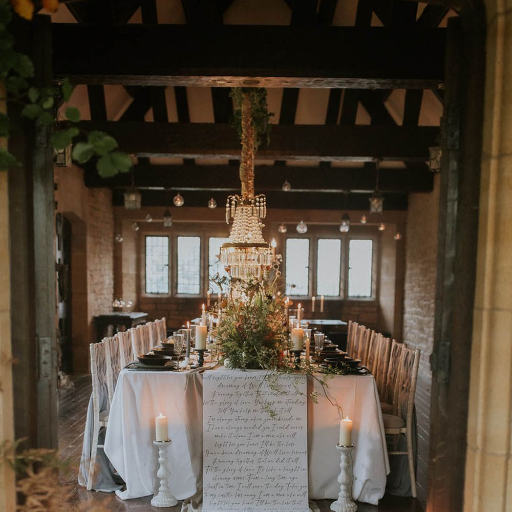 Grand table with large chandelier, pillar candles, foliage and large letter decor in the reception room of Hooton Pagnell Hall