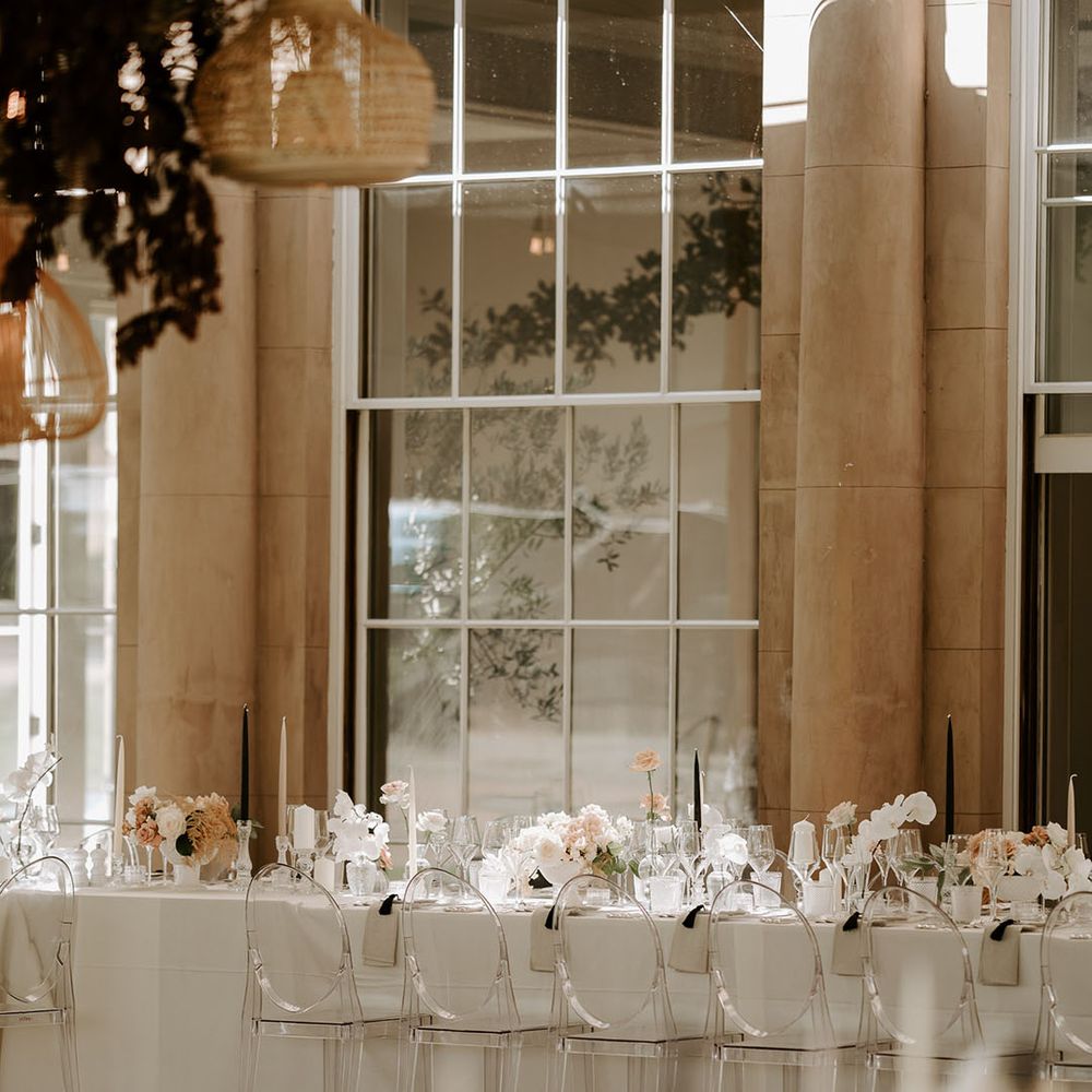 Neutral and black taper candles decorate the tablescape with pale pink and white wedding flowers 