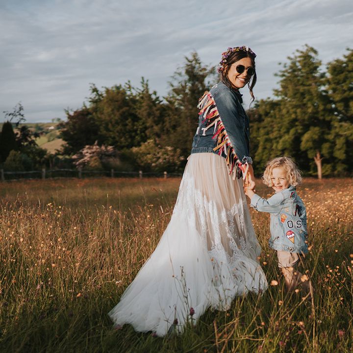 Bride in personalised denim jacket walks through fields with her son wearing personalised denim jacket 