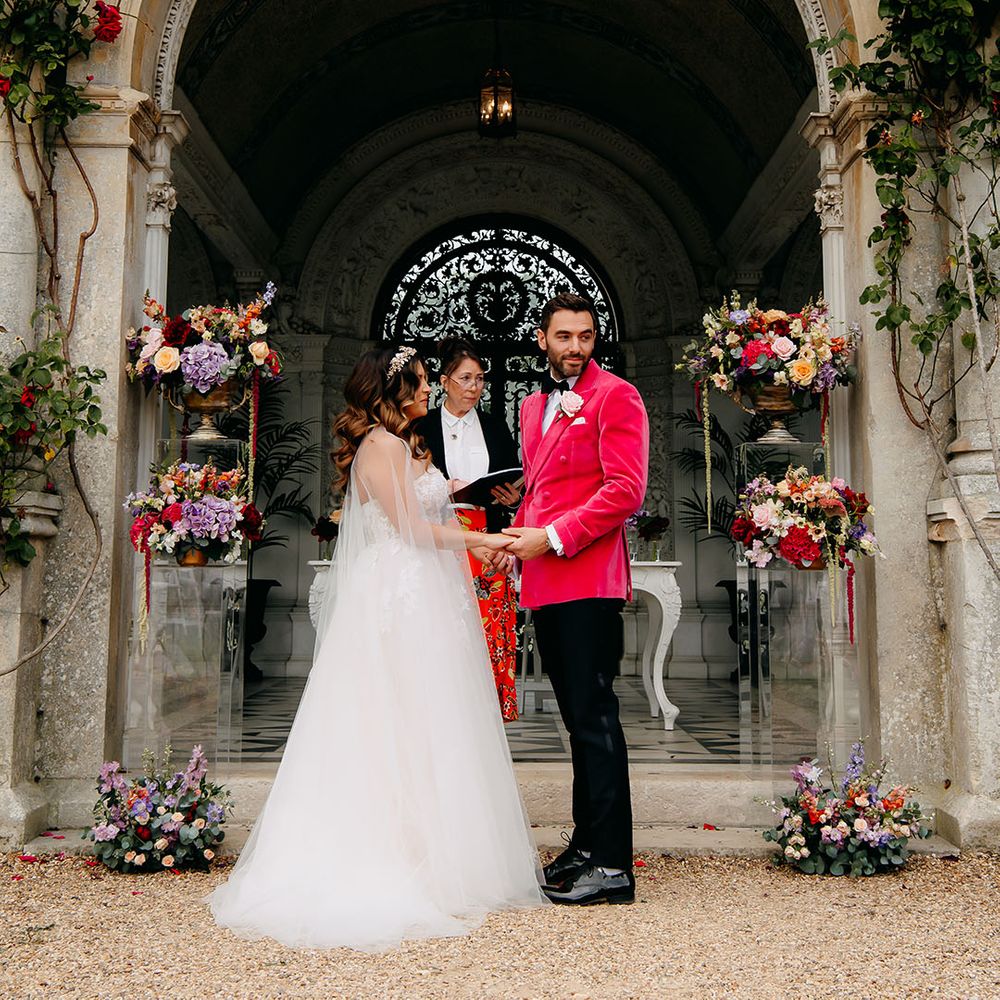 Bride and groom stand hiding hands for their civil ceremony at North Mymms Park wedding venue 