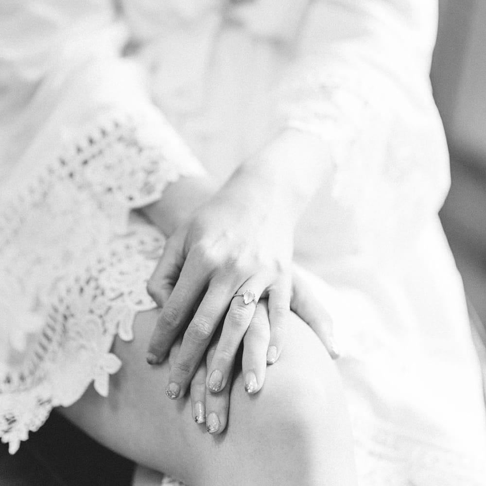 Bride wears sparkling nail polish and oval shaped diamond engagement ring in black & white photo