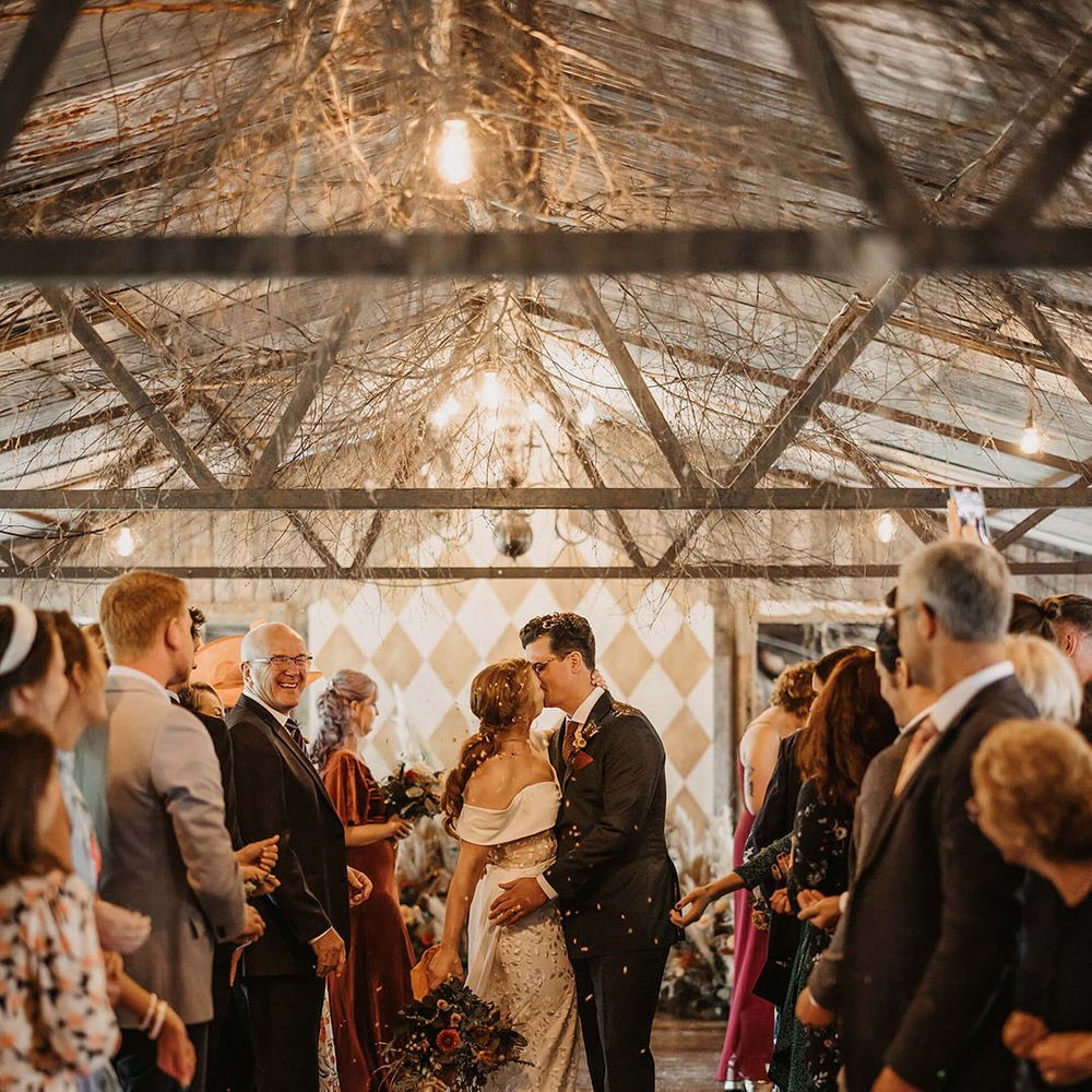 Bride & groom walk through colourful confetti exit at The Dreys after bespoke wedding ceremony 