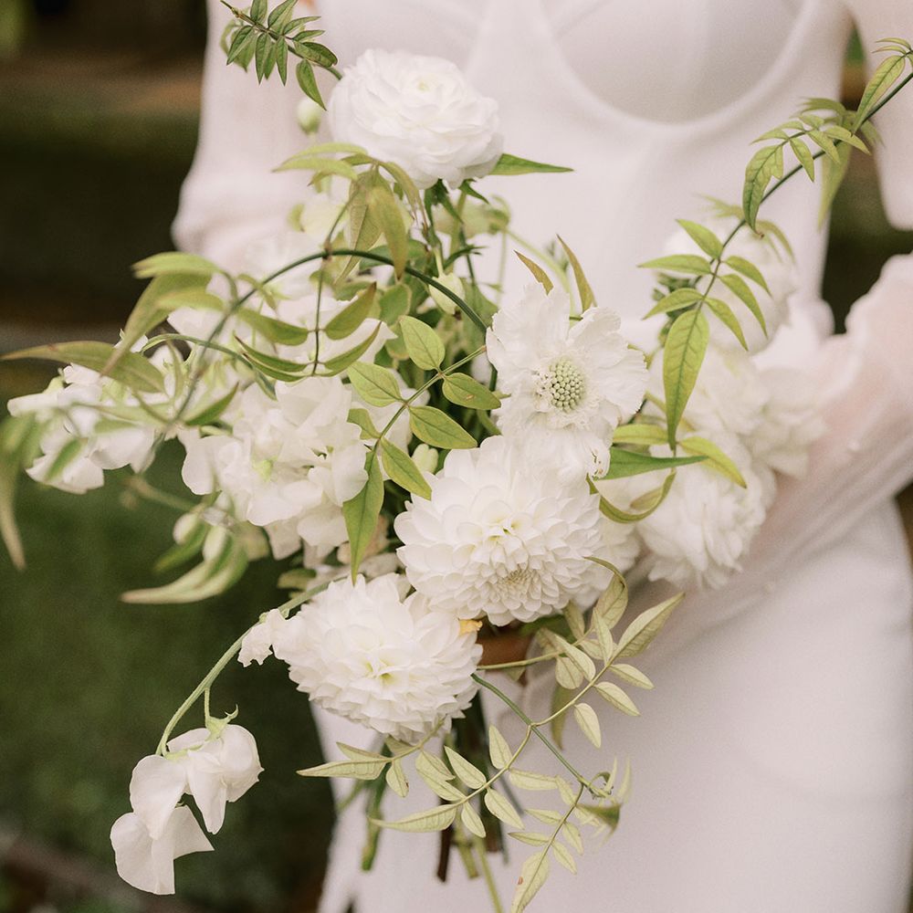 White dahlias and sweet peas wedding bouquet for the bride in a strapless wedding dress from Bon Bride 