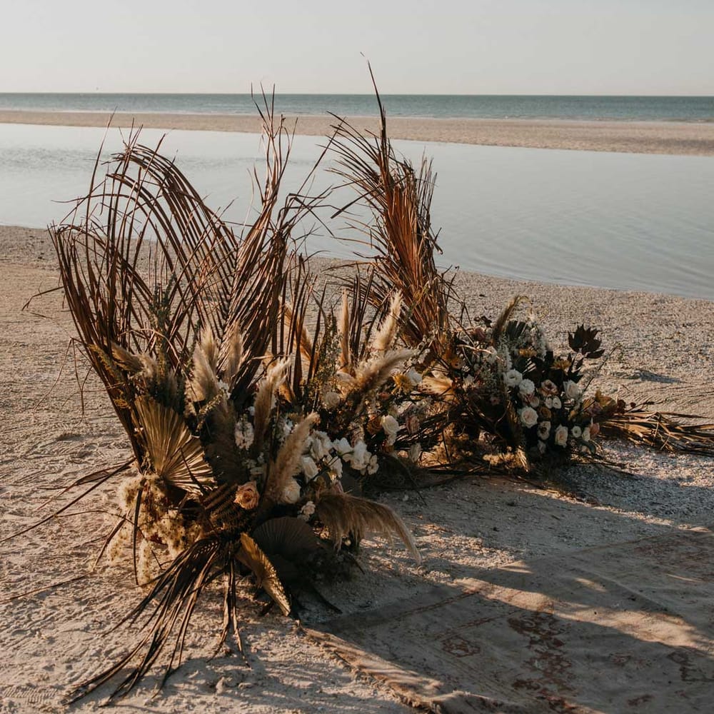 Large pampas grass and dried flower wedding flower arrangement on beach at destination wedding in Mexico 