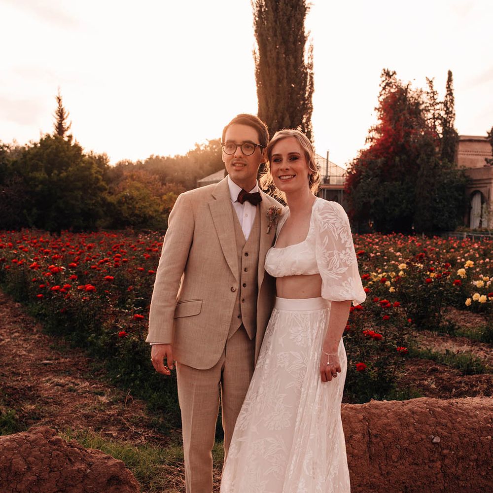 Groom in cream suit with red bow tie with the bride in bridal separates from Grace Loves Lace at Morocco wedding 