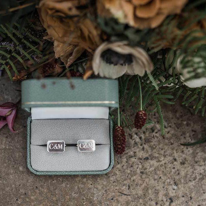 Personalised silver wedding cufflinks in sage green cufflinks box next to dried wildflower wedding bouquet at Buxted Park