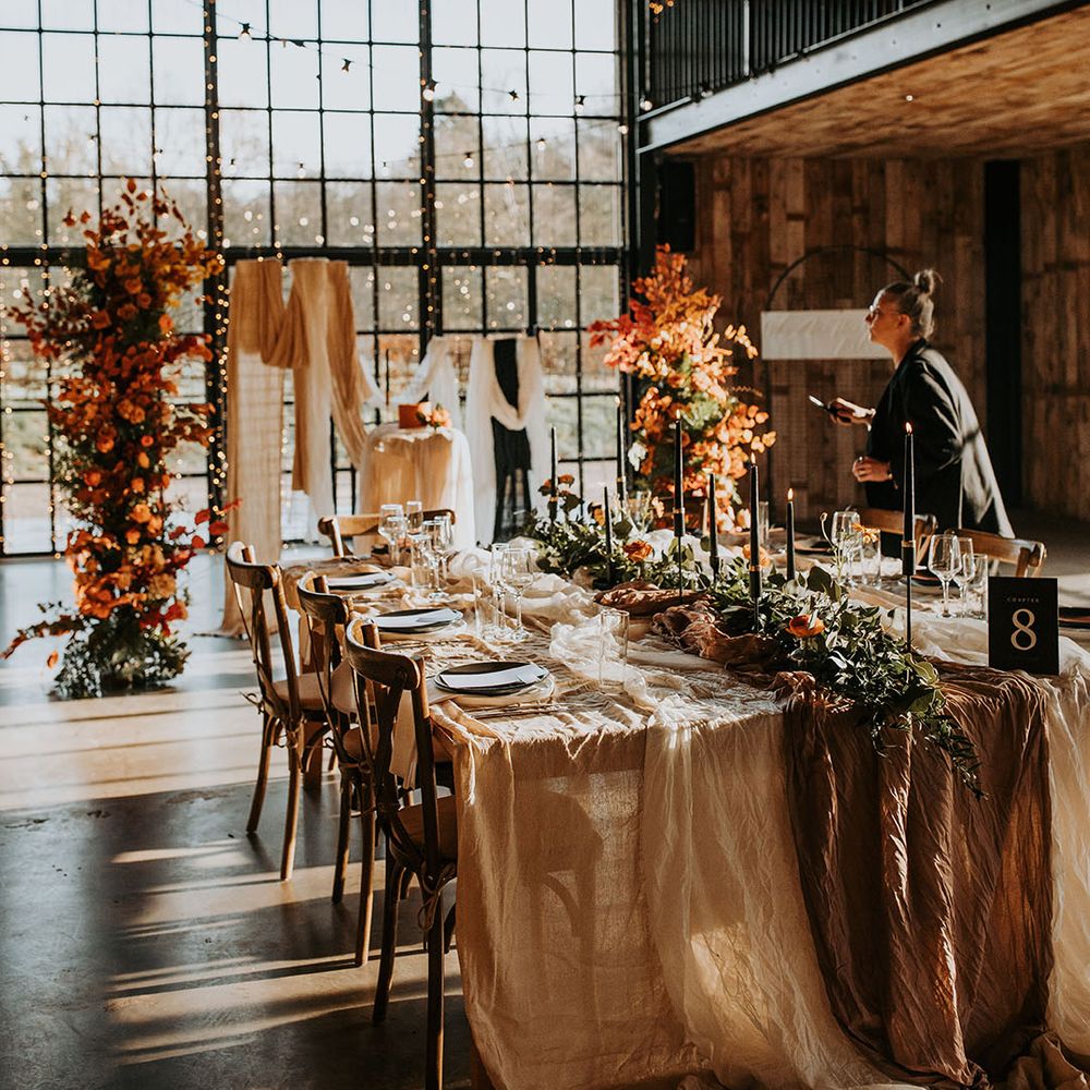 Autumnal wedding tablescape with orange flower decorations and twinkling fairy lights 