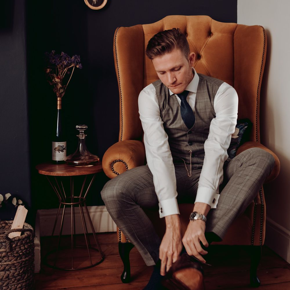 Groom on wedding morning putting on his tan brogues 