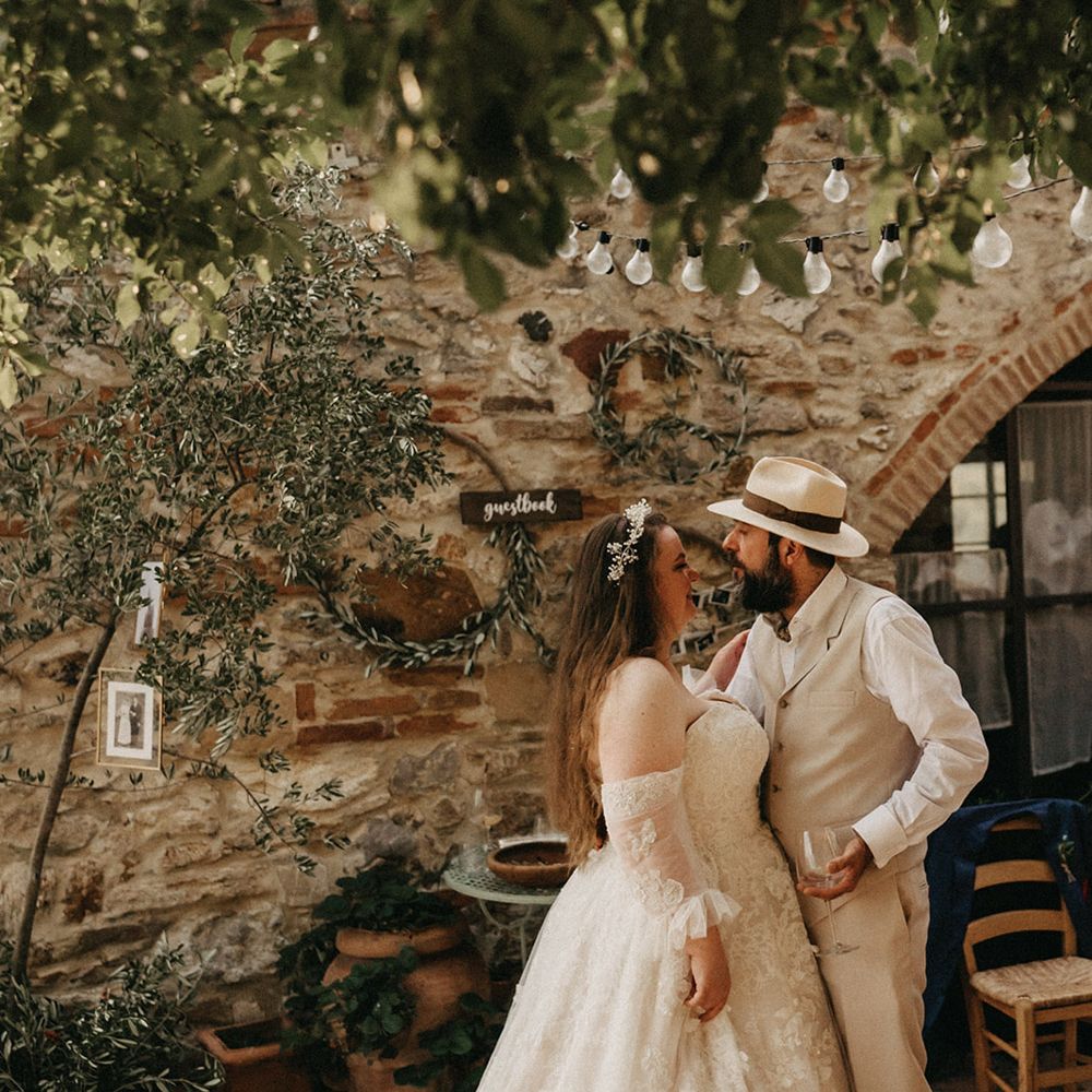 Bride and groom standing in front of olive bouquet guestbook wall