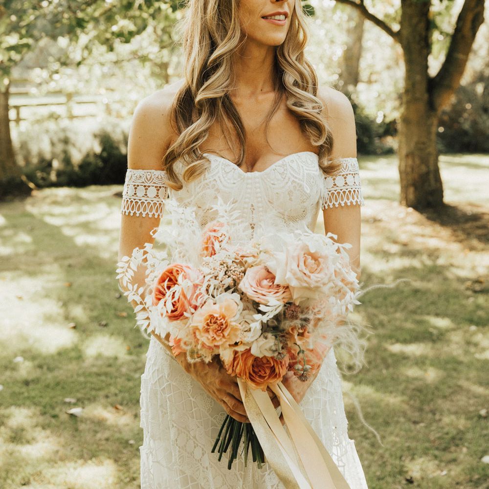 Boho bride in Clara Rude De Seine dress with white, pink and orange rose bridal bouquet with cream ribbon detail
