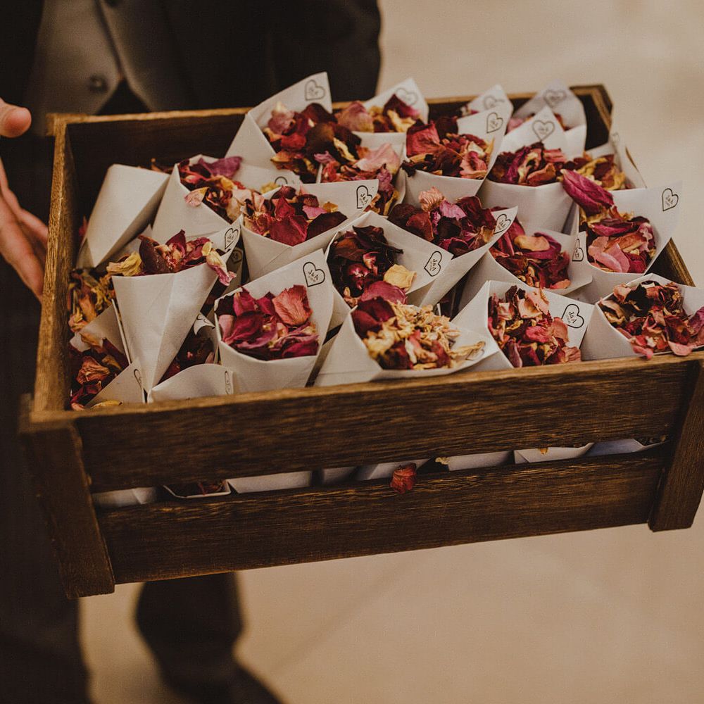 Groomsman holding confetti cones in wooden box