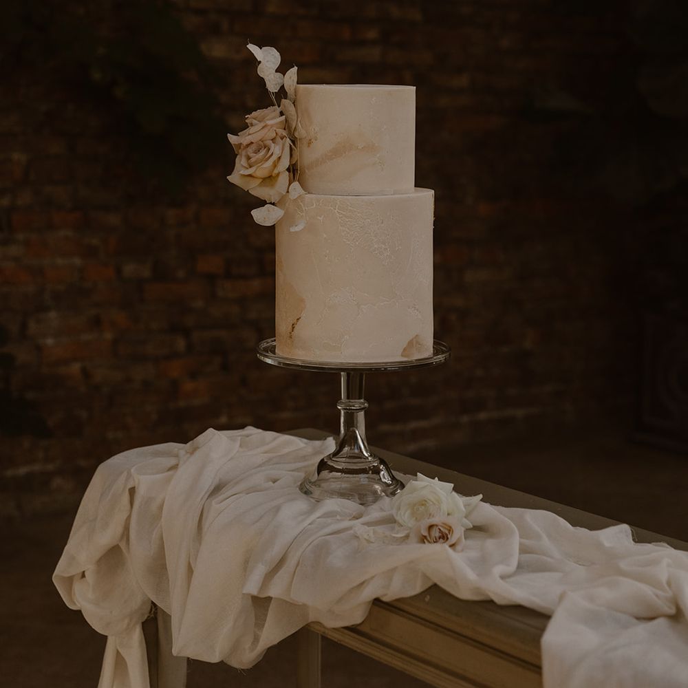 Two tiered off white marble effect wedding cake with rose decoration by Bohemian Bakehouse