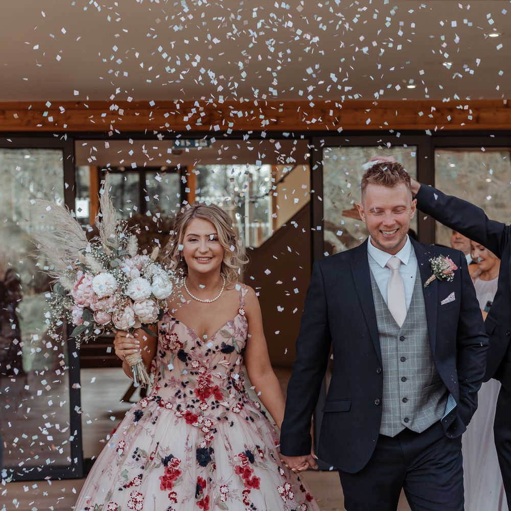 Bride & groom walk through confetti after their wedding ceremony