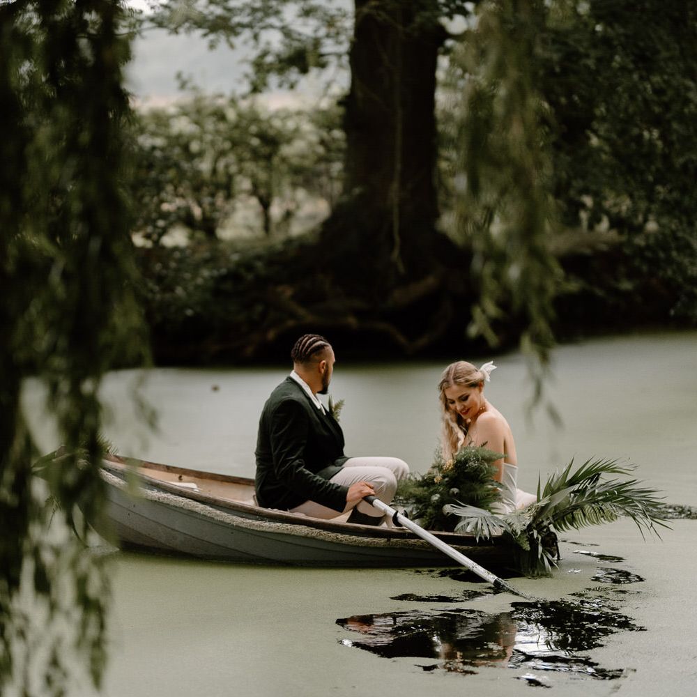 Bride and groom in a rowboat on a green algae covered lake for tropical wedding theme