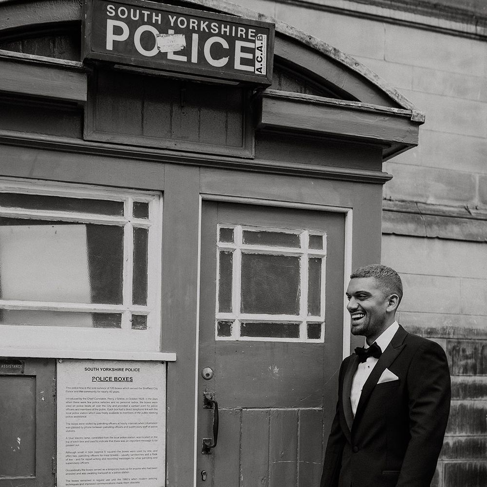 Stylish groom in a tuxedo standing outside an old South Yorkshire Police station