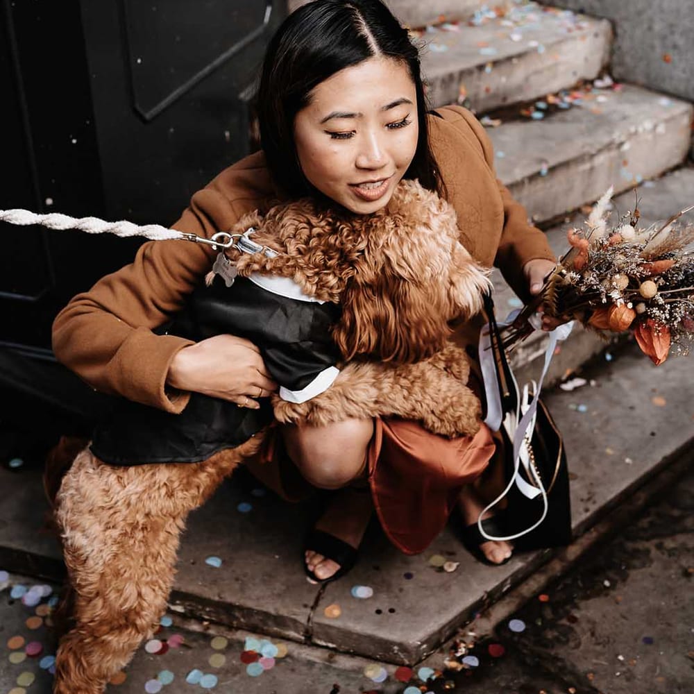 Bridesmaid is sharing the love and hugging dog dressed in his wedding outfit 