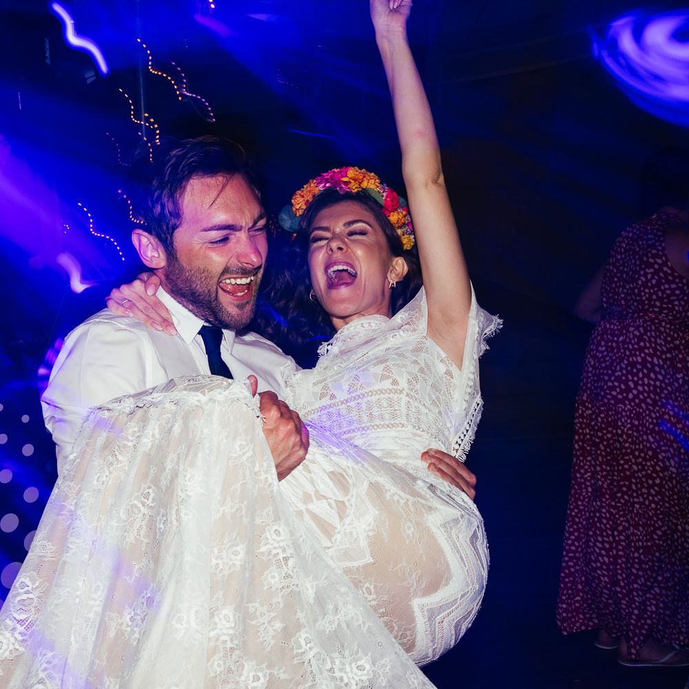 Bride in lace Grace Loves Lace wedding dress and flower crown and groom in white shirt dance during evening wedding reception at The Bridal Barn in Claverley