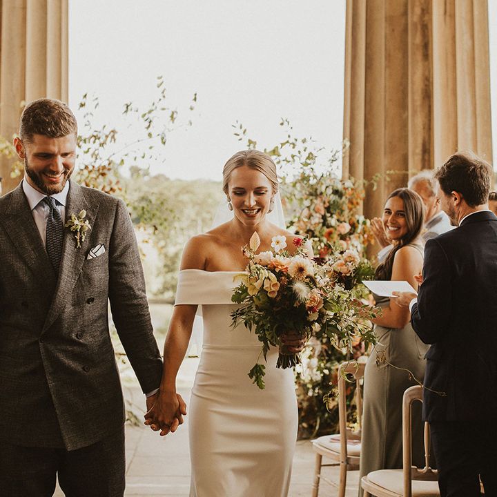 Bride & groom smile as they walk down the aisle holding hands on their wedding day