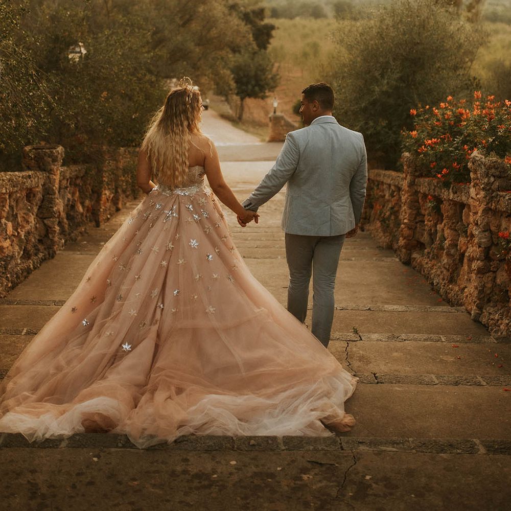 Bride & groom walk hand in hand as the sun shines around them in Mallorca
