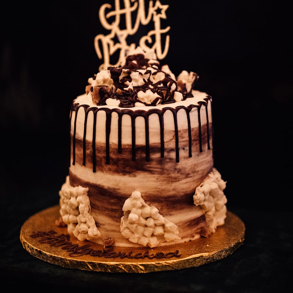 Semi naked chocolate drop effect wedding cake with wedding cake topper reading 'At Last'