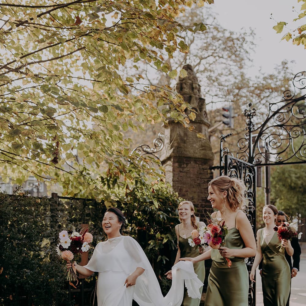 Bride walks along with her bridesmaids who hold her wedding cape | Irene Yap Photography