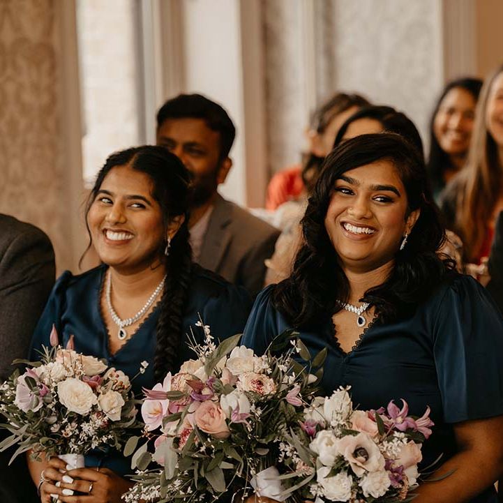 Bridesmaids in dark green bridesmaid dresses with button details and mixed floral bouquets