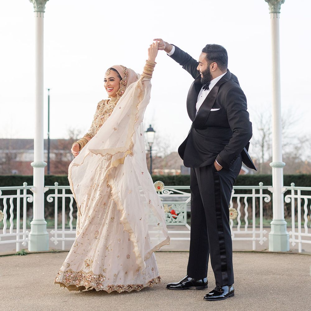 Groom who wears black tie spins his bride around as she wears traditional saree which blows in the wind