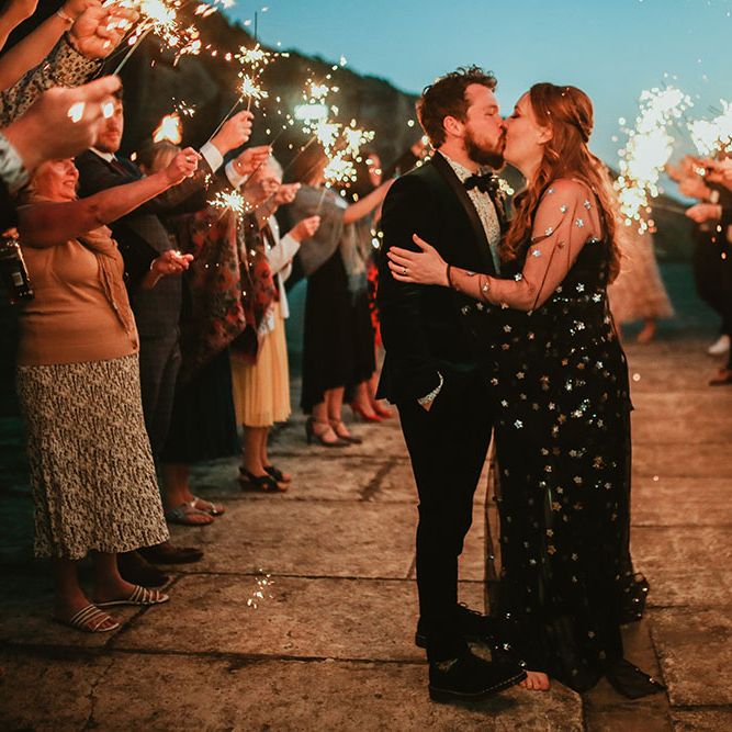 Bride & groom kiss during sparkler exit outdoors on their wedding day