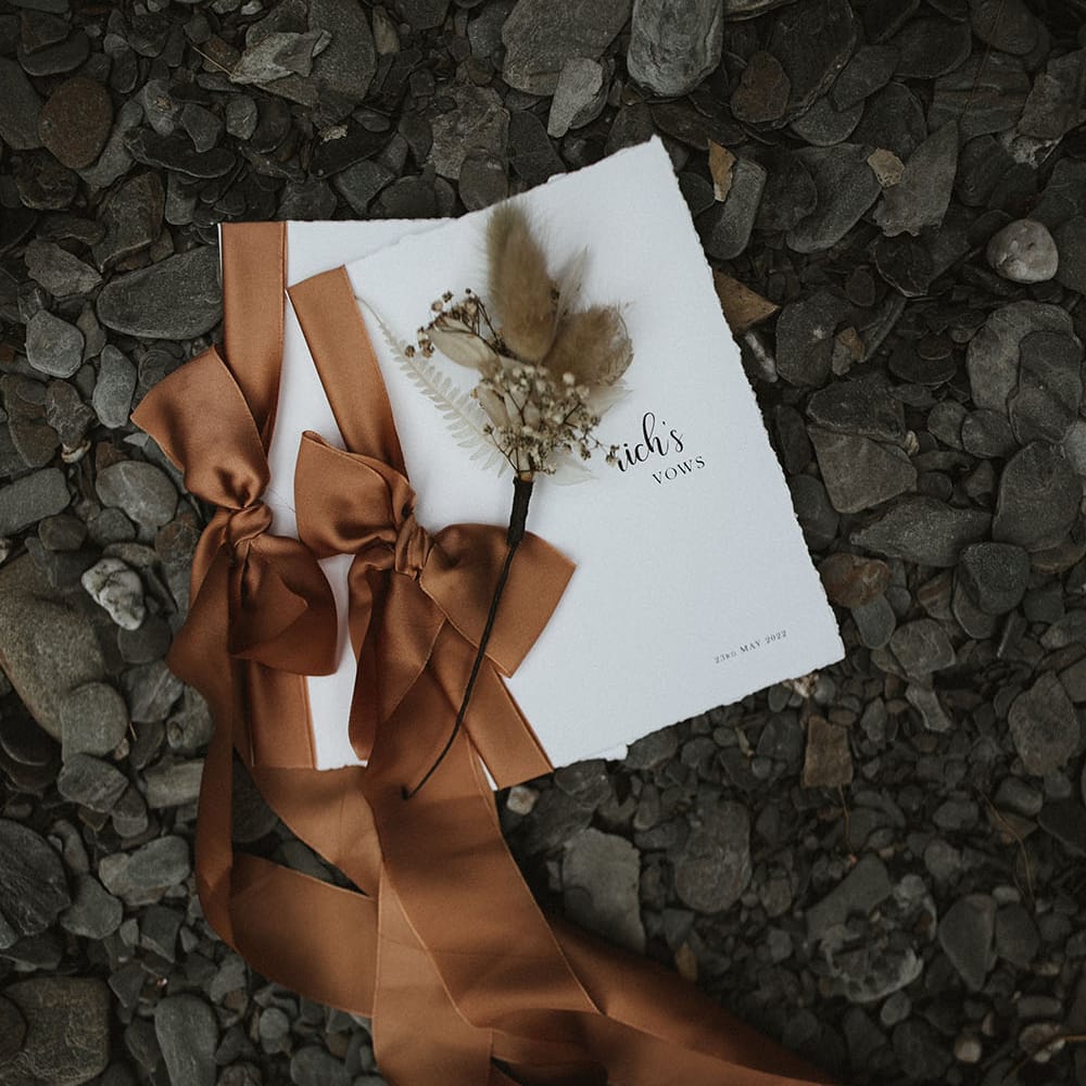 Vow wedding books in white tied with brass coloured silk ribbon and finished with dried floral arrangement 