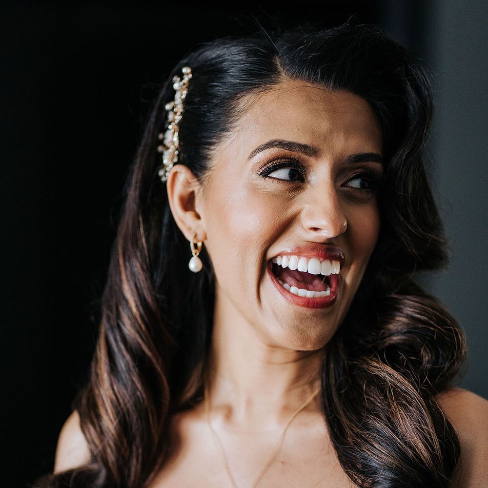 Indian bride wears natural makeup and pearl drop gold earrings with embellished hair accessory 