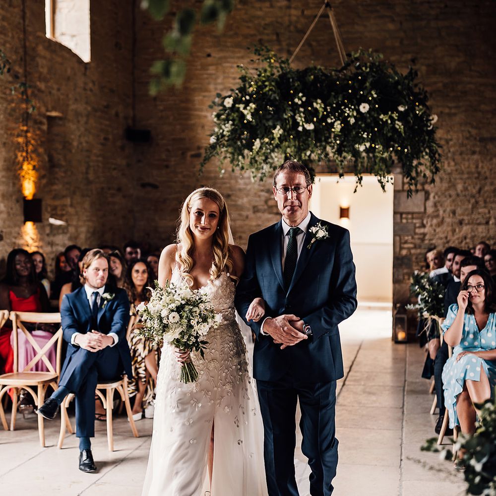 Father of the bride walks the bride in an applique wedding dress down the aisle 