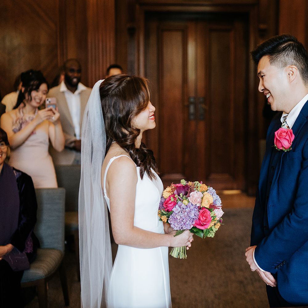Bride holds colourful bouquet whilst stood with her groom at The Old Marylebone Town Hall