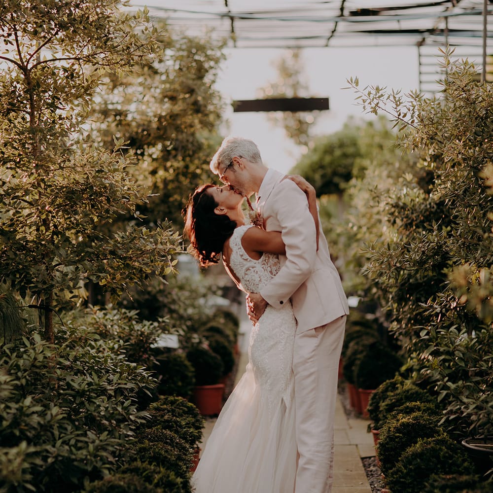 Bride and Groom embrace and kiss whilst surrounded by trees