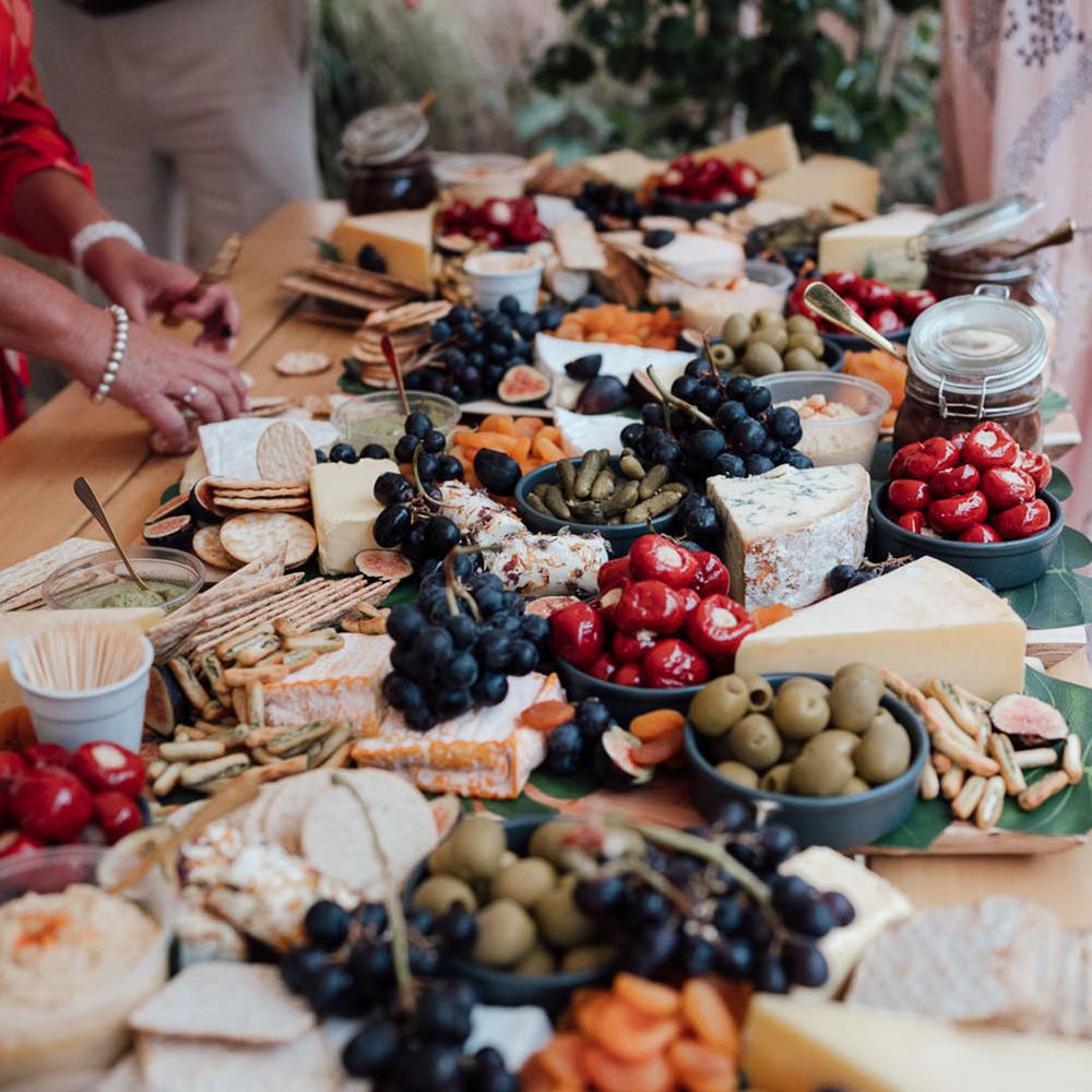 Grazing table with cheeses, crackers, grapes, dried fruits, olives, gherkins, and stuffed peppers 