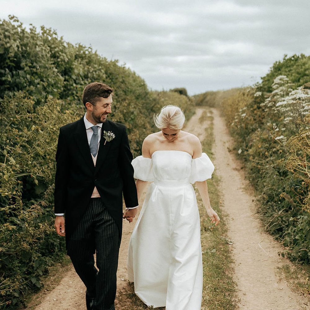 Bride in Jesus Peiro wedding dress walks alongside her groom in morning suit 