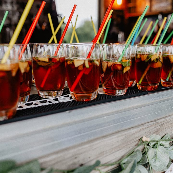 Glasses of Pimm's for the wedding guests with bright coloured paper straws 