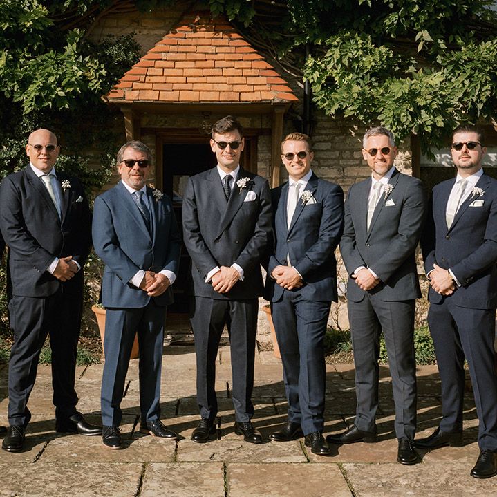 Groomsmen in navy suit with sage green ties with the groom in double breasted jacket and spotted tie all wearing sunglasses for the autumn wedding 