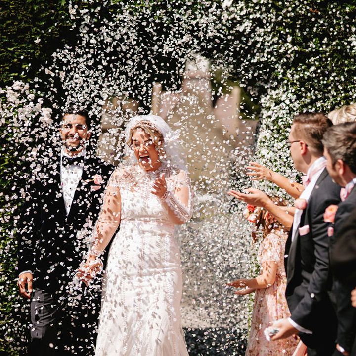 Wedding guests throw white confetti over the bride and groom at black tie luxury wedding 