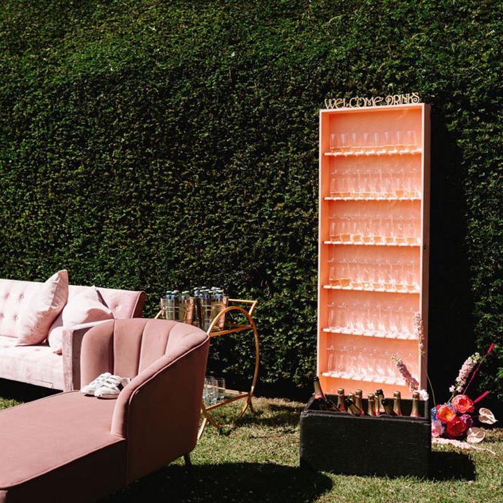 Pink and blue wedding seating area inspired by Morocco with sofas, champagne, and pink glasses for guests 