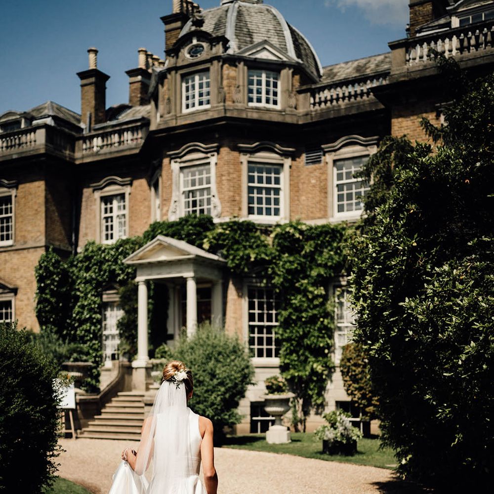 Bride in stunning and traditional sleeveless wedding dress walking up to the Surrey wedding venue 