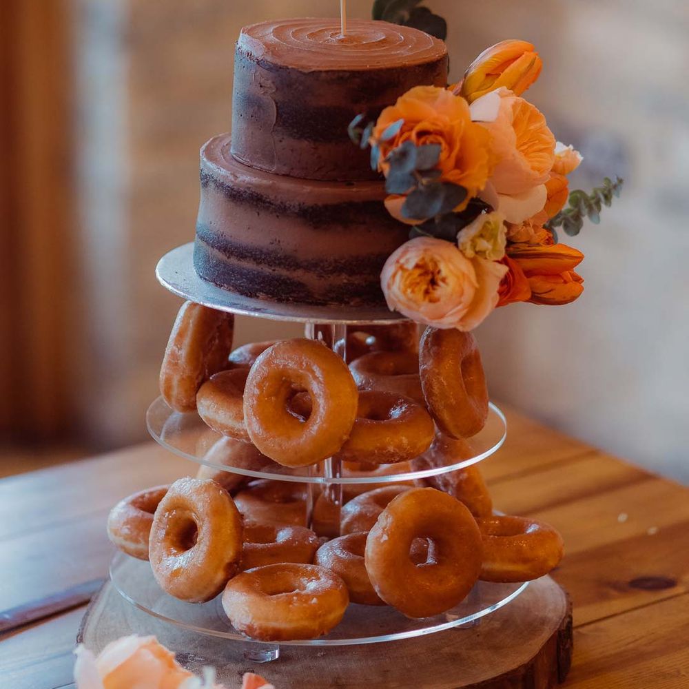Donut tower wedding cake with laser cut wedding cake topper and orange garden rose cake decorations at Kingscote Barn Tetbury 
