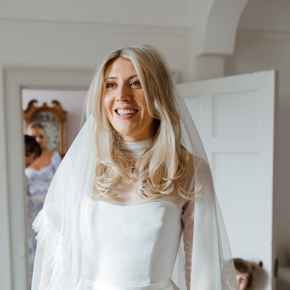 Bride in strapless gown with mesh overlay top and ruffle embroidered wedding veil 